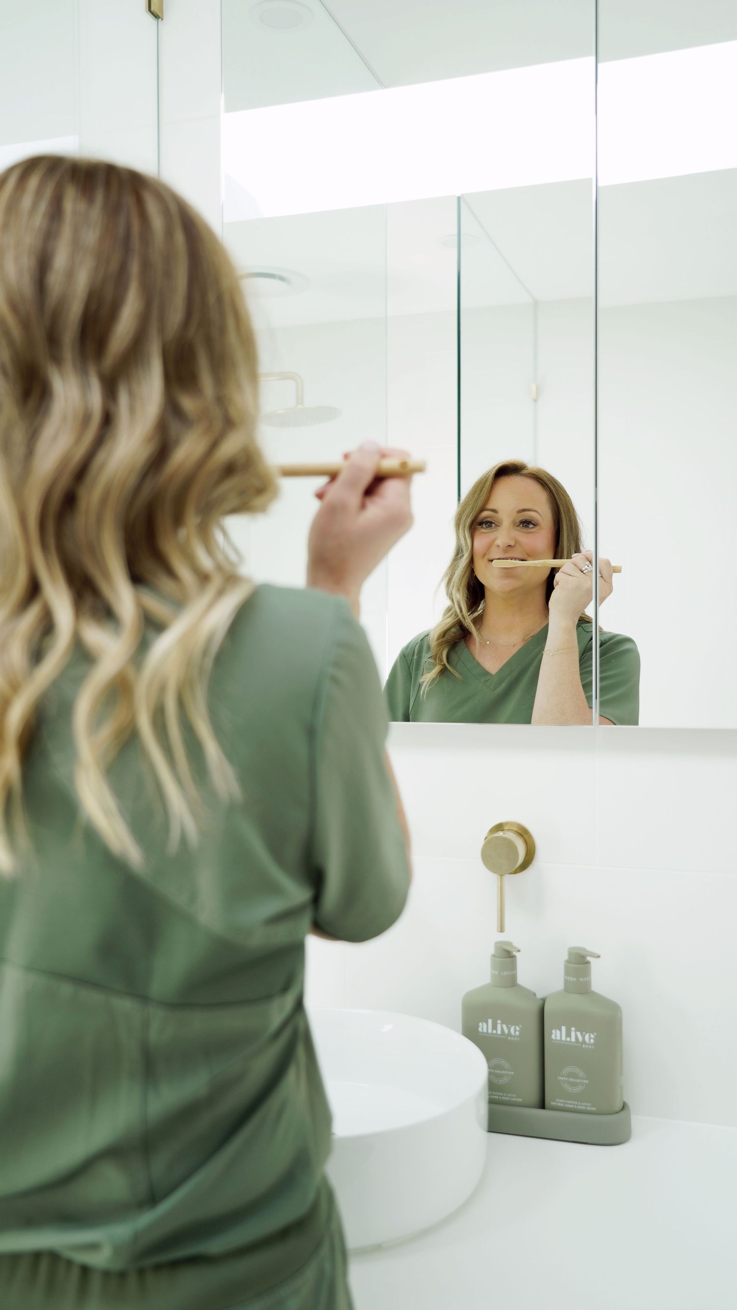 Modern bathroom interior with person brushing teeth at white vanity with mirror.