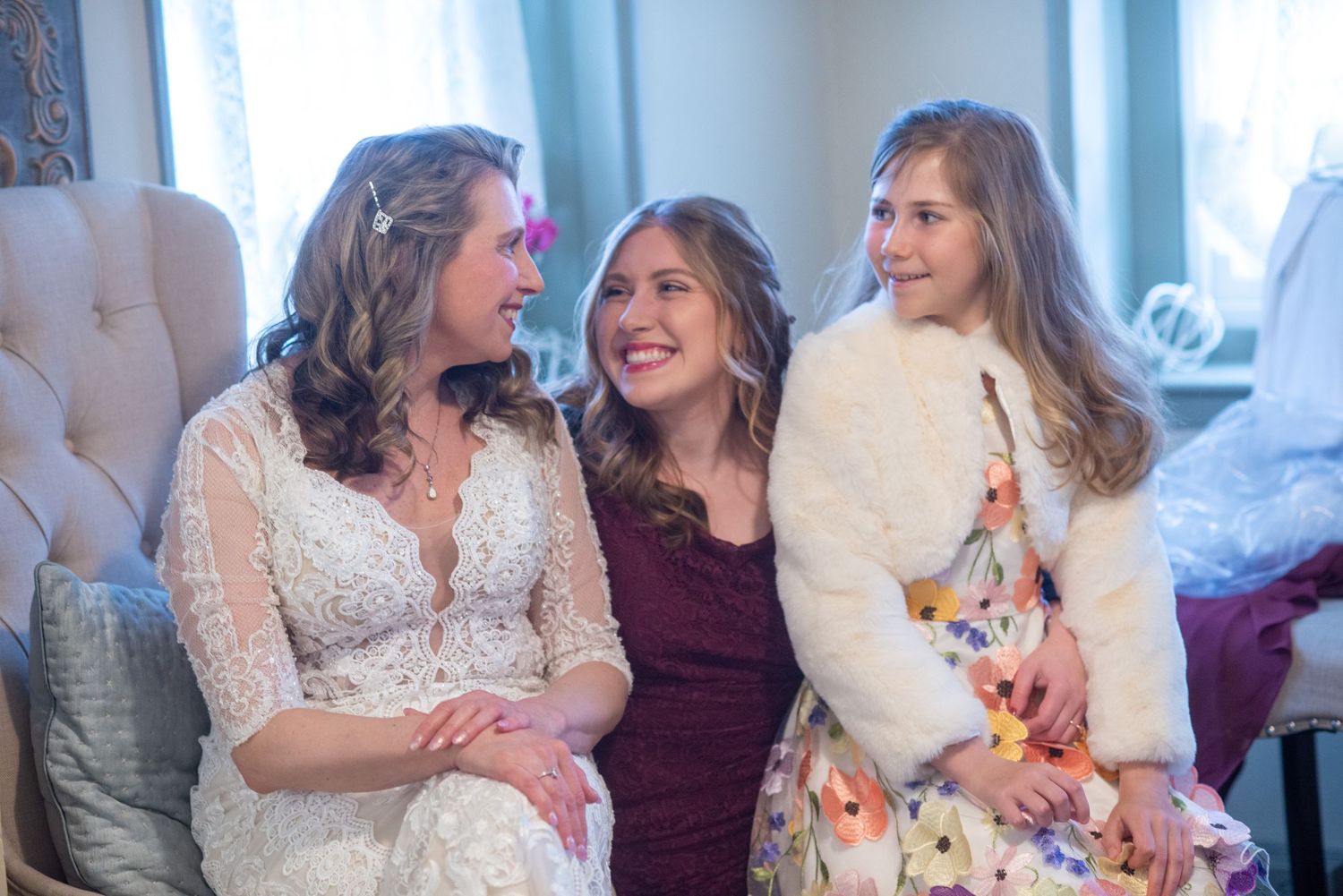 Three women share joyful moments together in a luxurious blue-tinted interior setting.