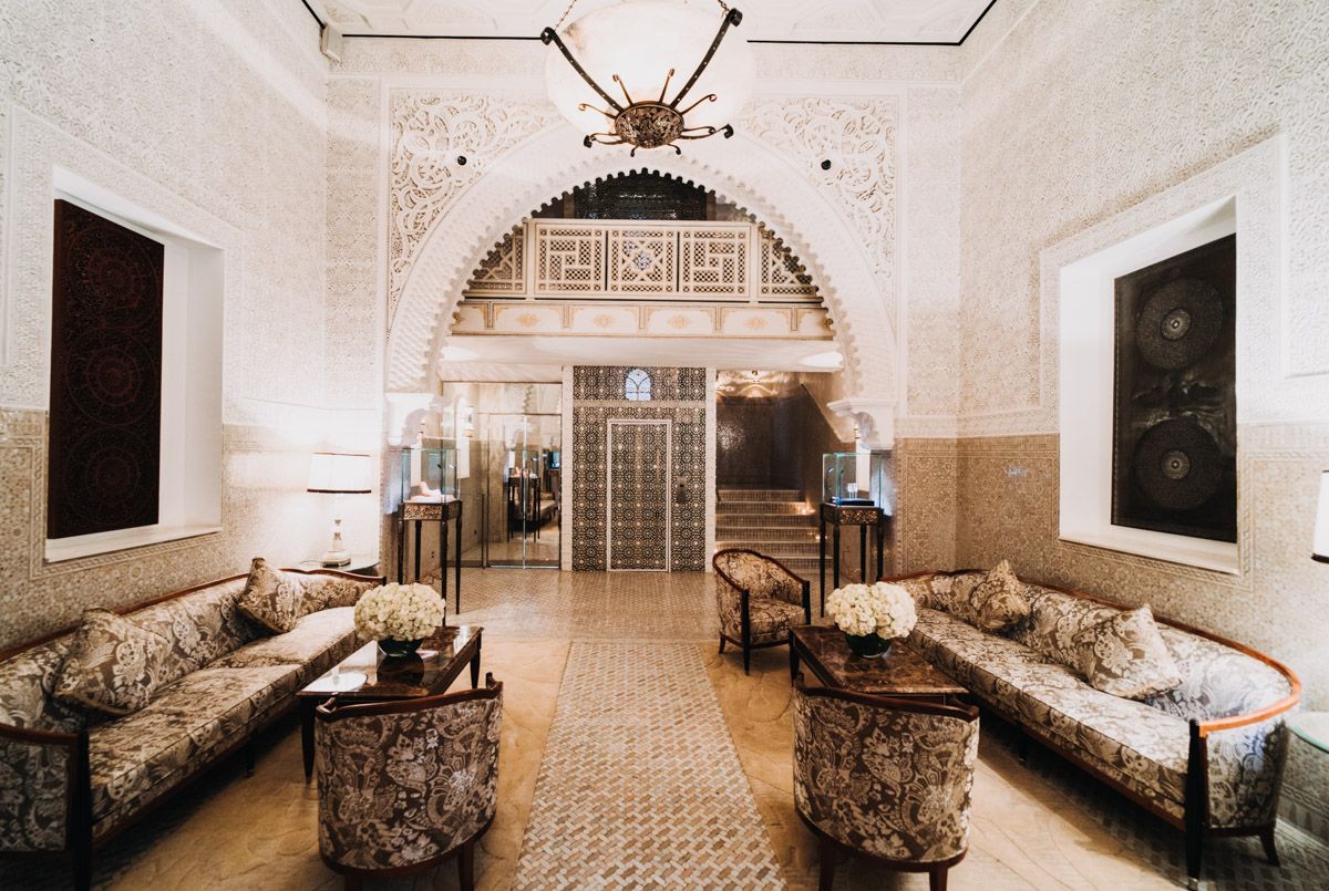 Elegant Moroccan-style sitting room with ornate archway and traditional seating adorned with decorative cushions.