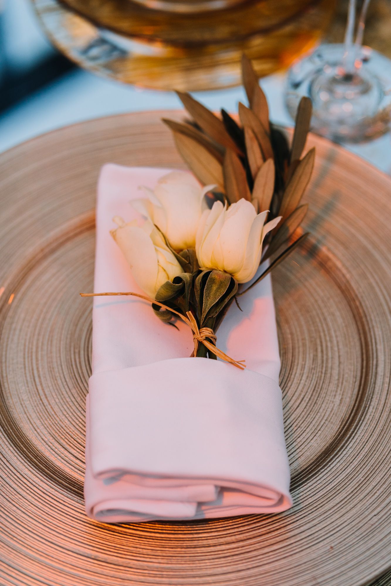 Elegant table setting with white napkin and floral decoration on a gold-rimmed plate.