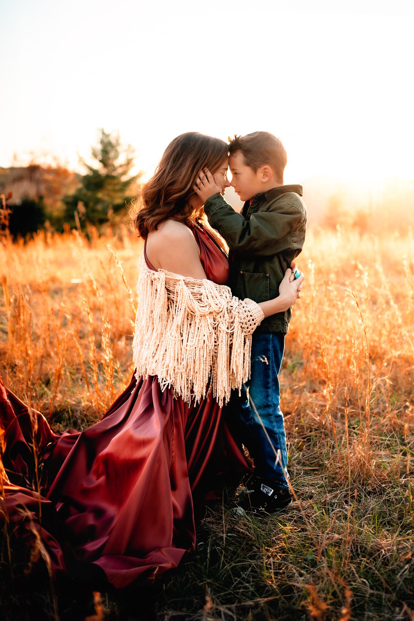 Intimate moment captured in autumn field with burgundy dress and fringed shawl.