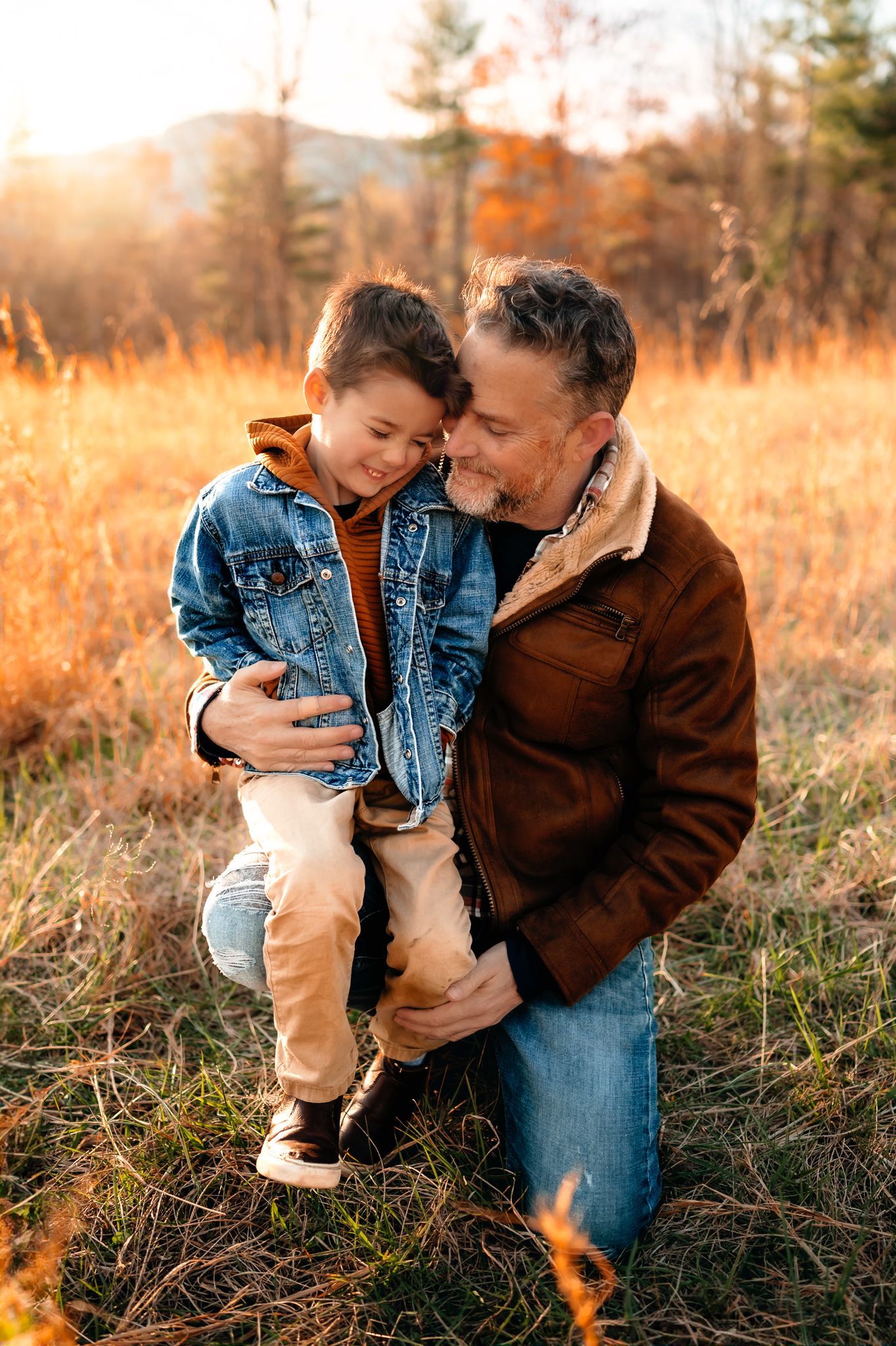 Sweet outdoor moment between parent and child in denim jackets during golden sunset in autumn field.