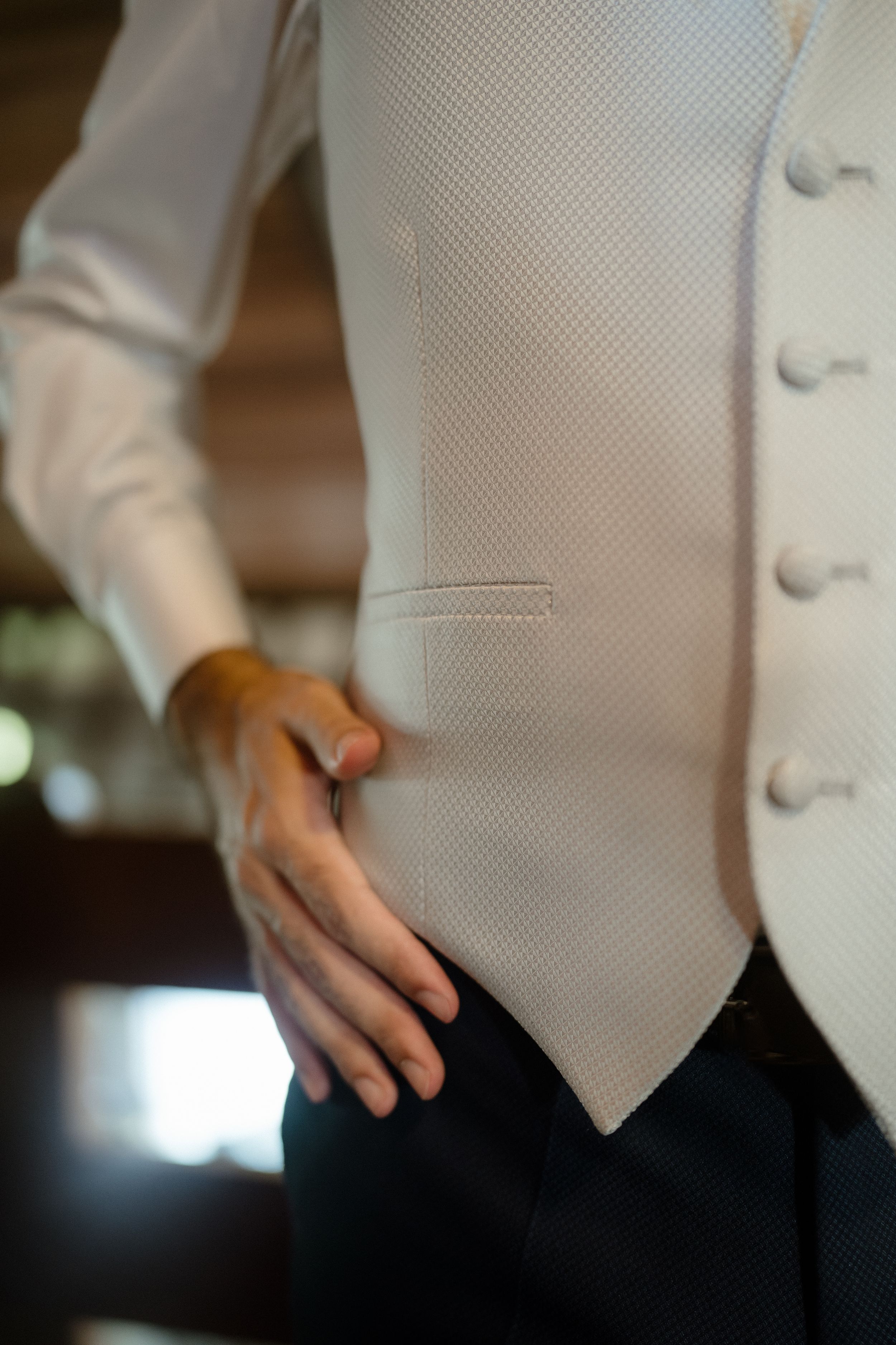 Close-up detail of a white formal vest with buttons against dark trousers.
