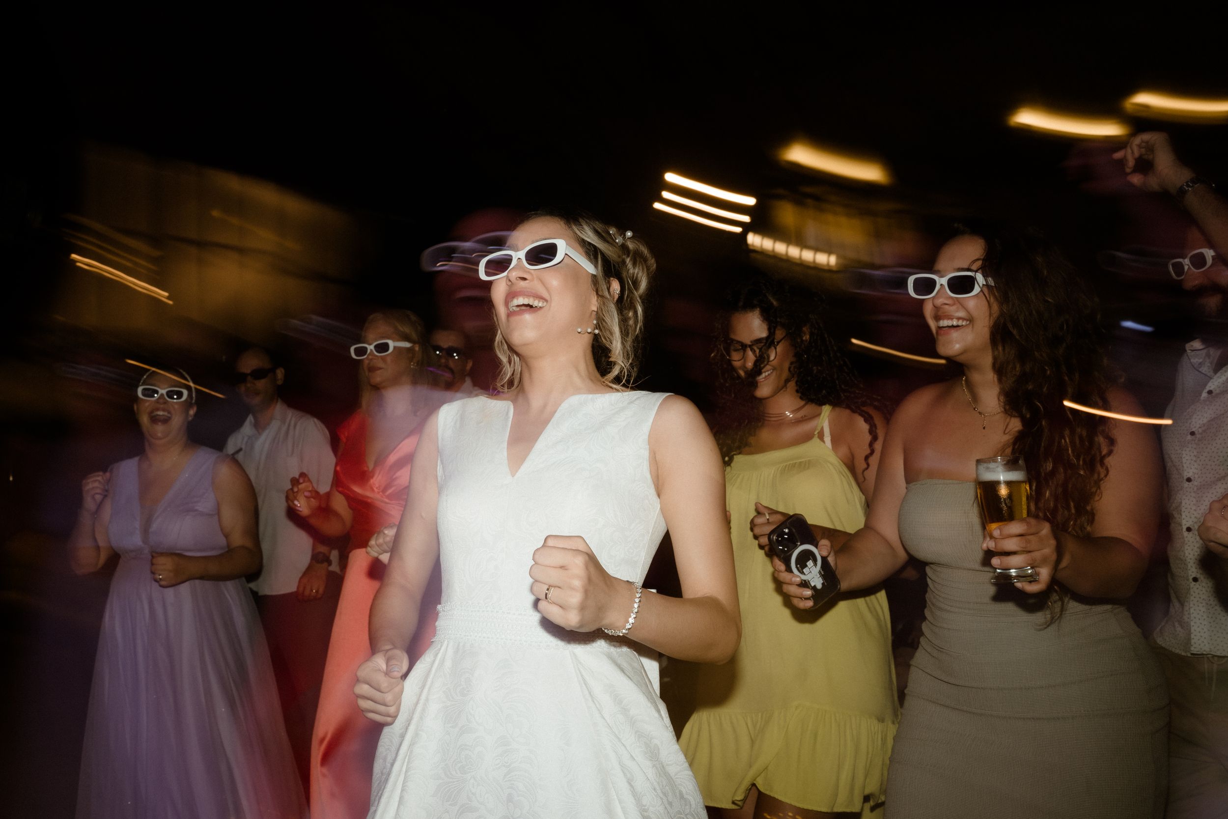 Party scene with dancers in sunglasses enjoying themselves under ambient lighting.