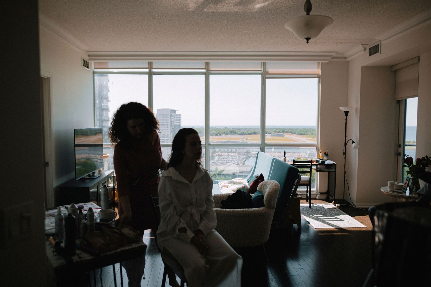 Silhouetted figures by large window in modern apartment setting.