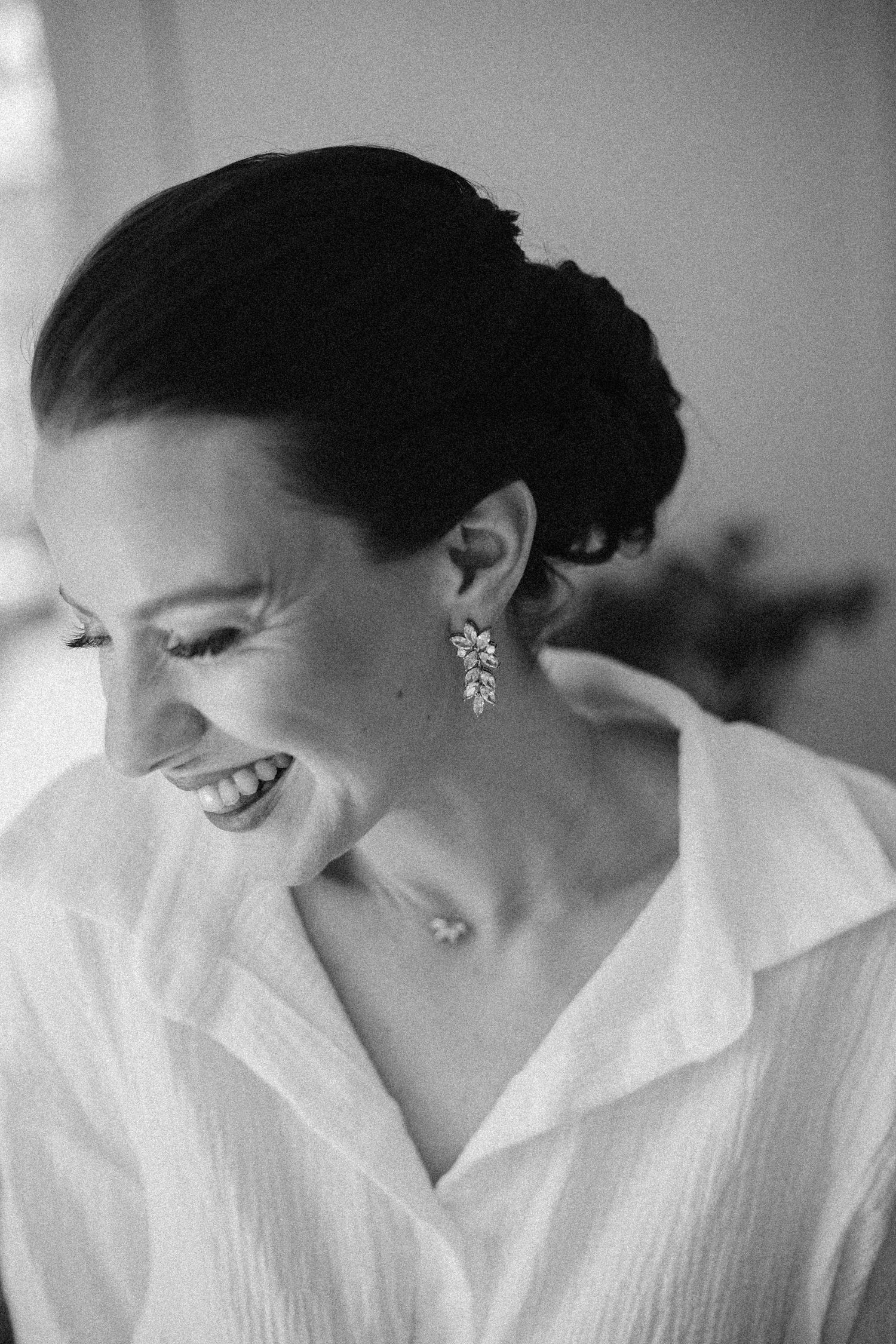 Black and white portrait of person laughing while wearing sparkly earrings.