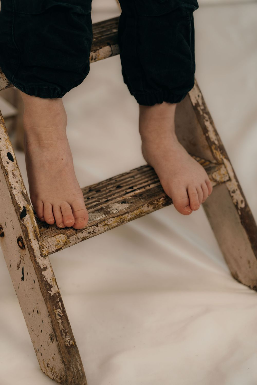 The feet of a 2 year old boy on small wooden steps.