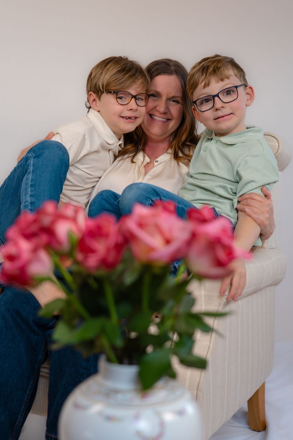 A mother and her children smiling with a beautiful bunch of roses in the foreground.