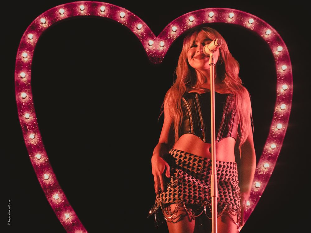 Performance shot with illuminated heart prop and dramatic red lighting on stage.