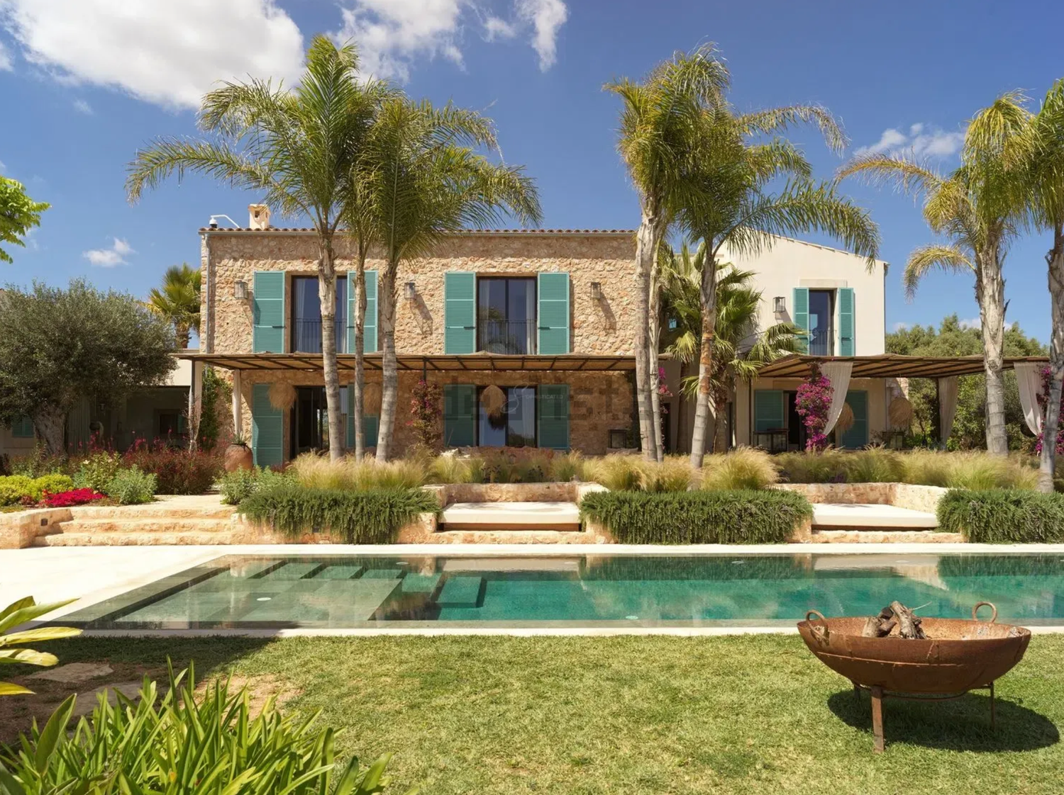 Luxury hillside homes with panoramic ocean views at sunset along mountainous coastline.