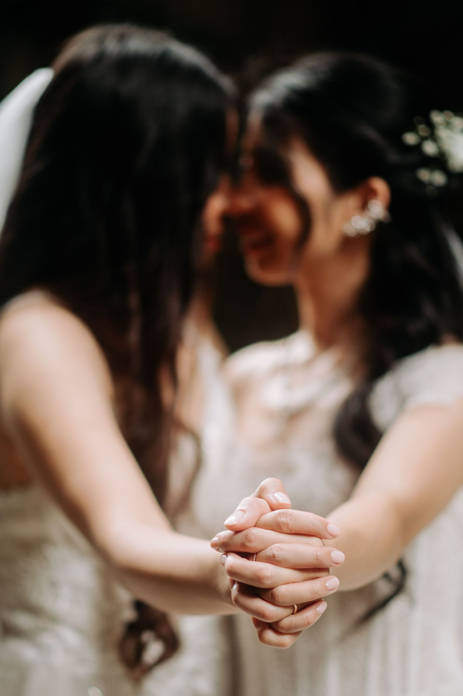 Close-up of joined hands during intimate wedding moment.