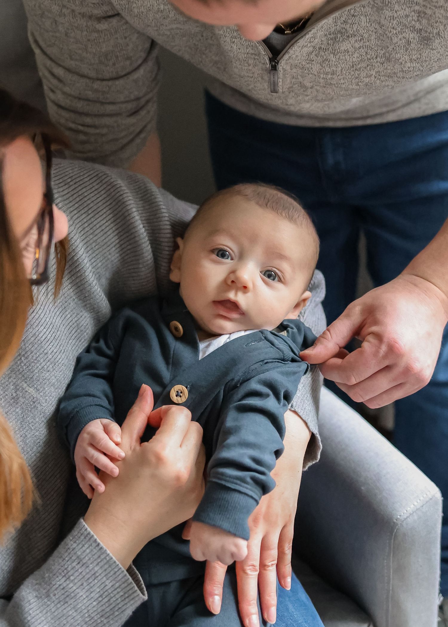 An image of a baby's face while his parent snuggle him and show affection.