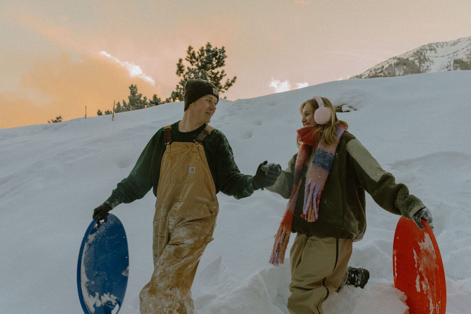 Silhouettes of people walking together in snowy mountain terrain during sunset.