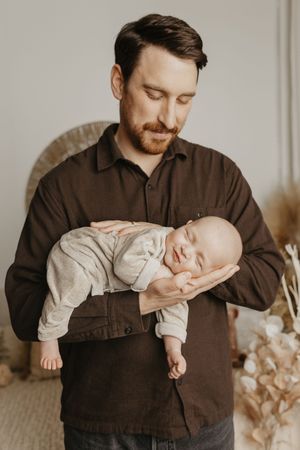 A series of candid moments showing a father in a brown shirt cradling and bonding with his newborn baby.