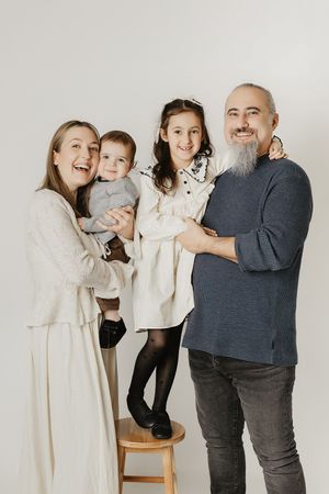 A playful family photo series showing candid moments of laughter and embraces against a light background.