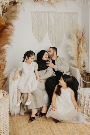 Playful family photo sequence on a cream couch with boho macrame wall decorations.