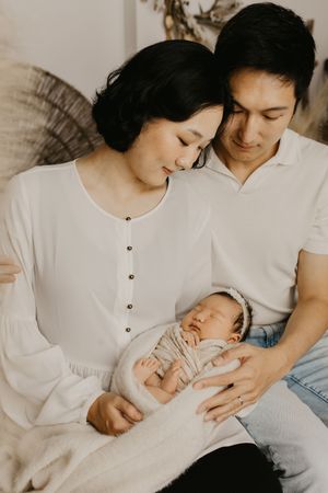 Intimate family portrait in white clothing showing tender moments with a newborn baby.