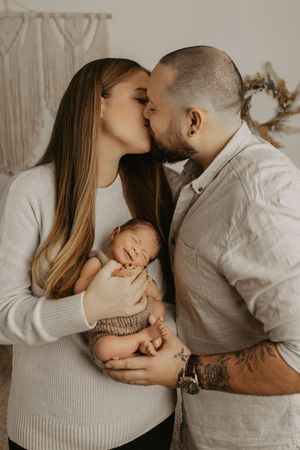 Tender family moment captured in neutral tones against minimalist background.