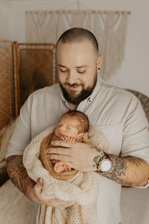 Tender newborn session featuring gentle holding poses in cream and white tones.