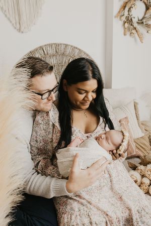 Family portrait series with pampas grass decor showing tender moments with a sleeping infant.