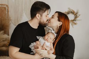 Tender family moment captured in warm sepia tones showing intimate connection between parents and baby.