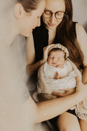 Intimate close-up shots of parents bonding with their sleeping newborn in soft natural light.
