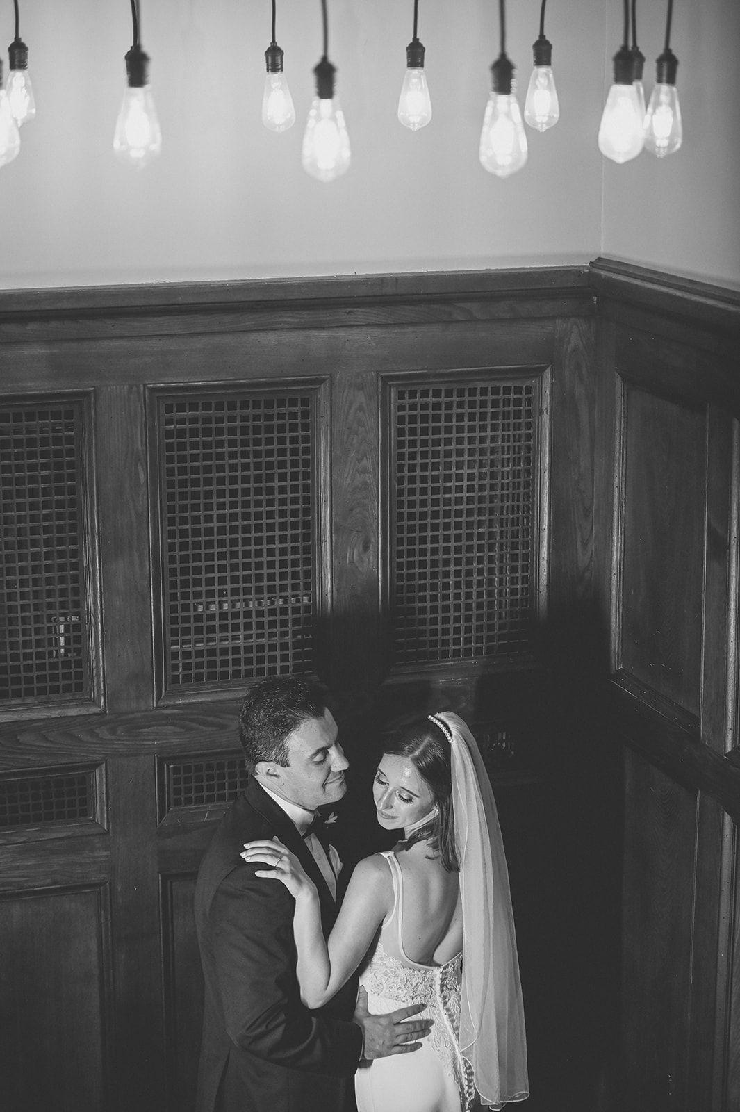 A dramatic black and white wedding photo sequence shows a couple sharing intimate moments under hanging light bulbs at the renaissance hotel