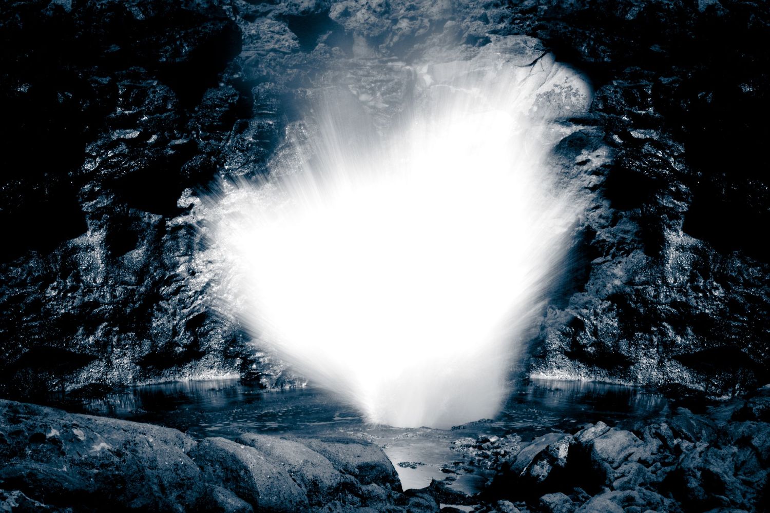 A bright glowing heart-shaped light illuminates a dark volcanic rock scene in ethereal blue tones.