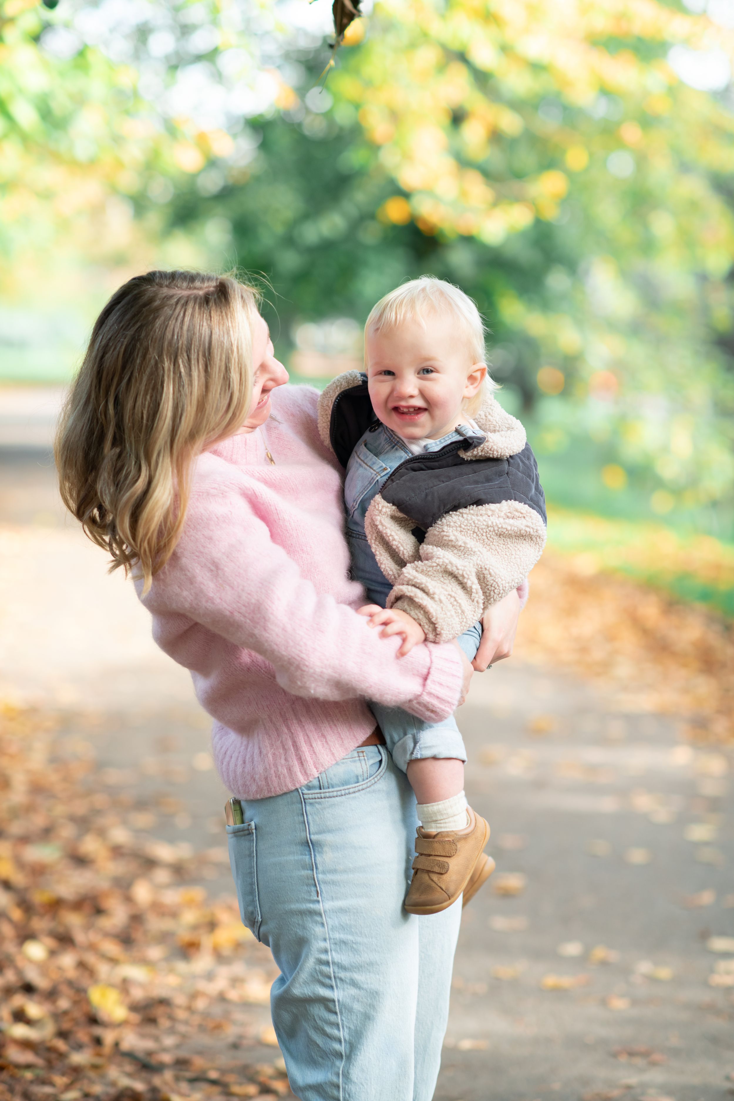 A mother giggles with her toddler son in a sunny autumn setting at Valley Gardens, Harrogate.