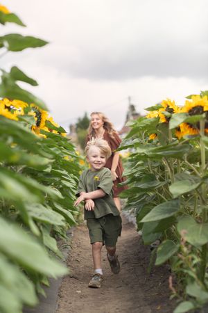 A mother and son running through sunflowers
