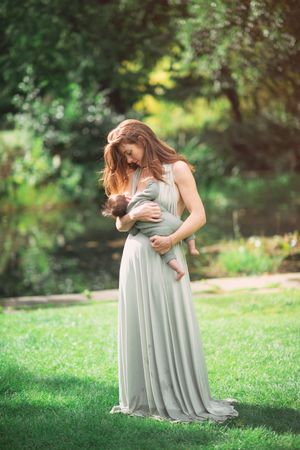 A mother holding her newborn baby in a beautiful long green dress