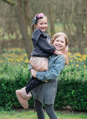 Two children playing outdoors in a meadow with yellow wildflowers on a spring day.