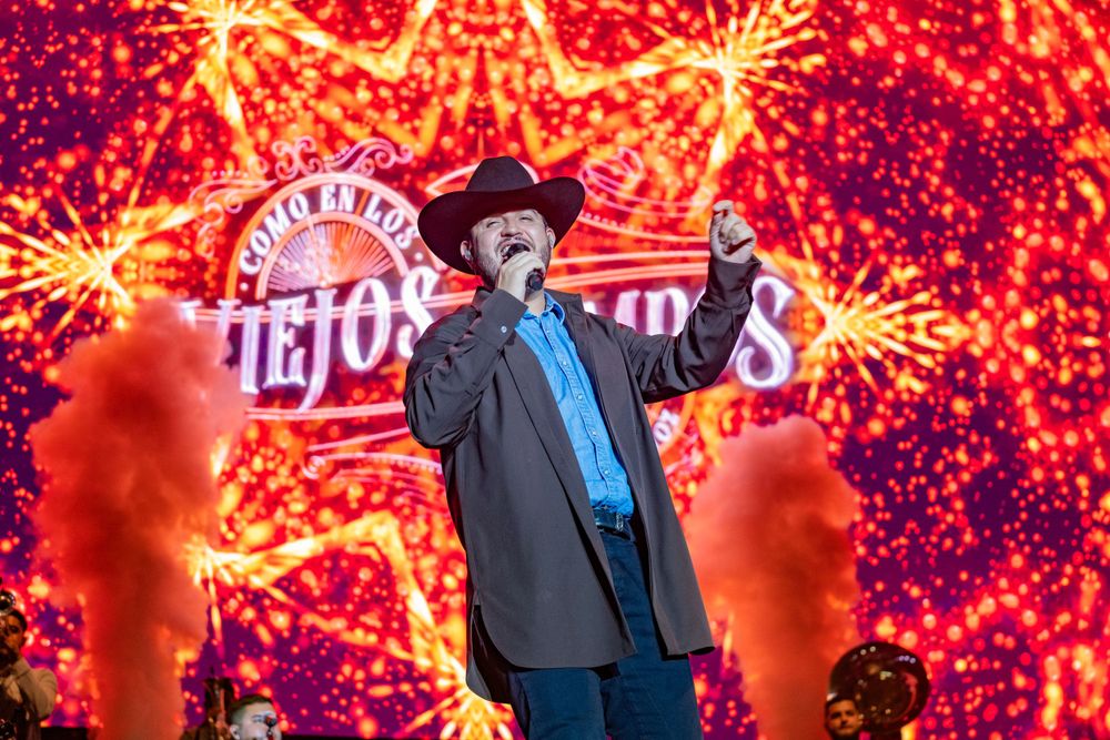 Performer on stage with dramatic red firework effects display in background.