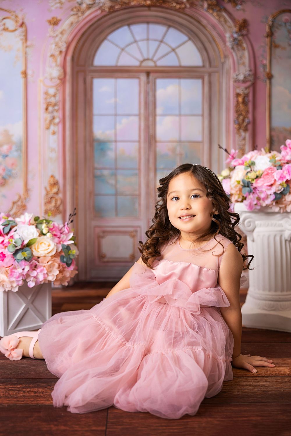 Pink-themed portrait session with elegant floral decor and arched windows in a luxurious interior setting.