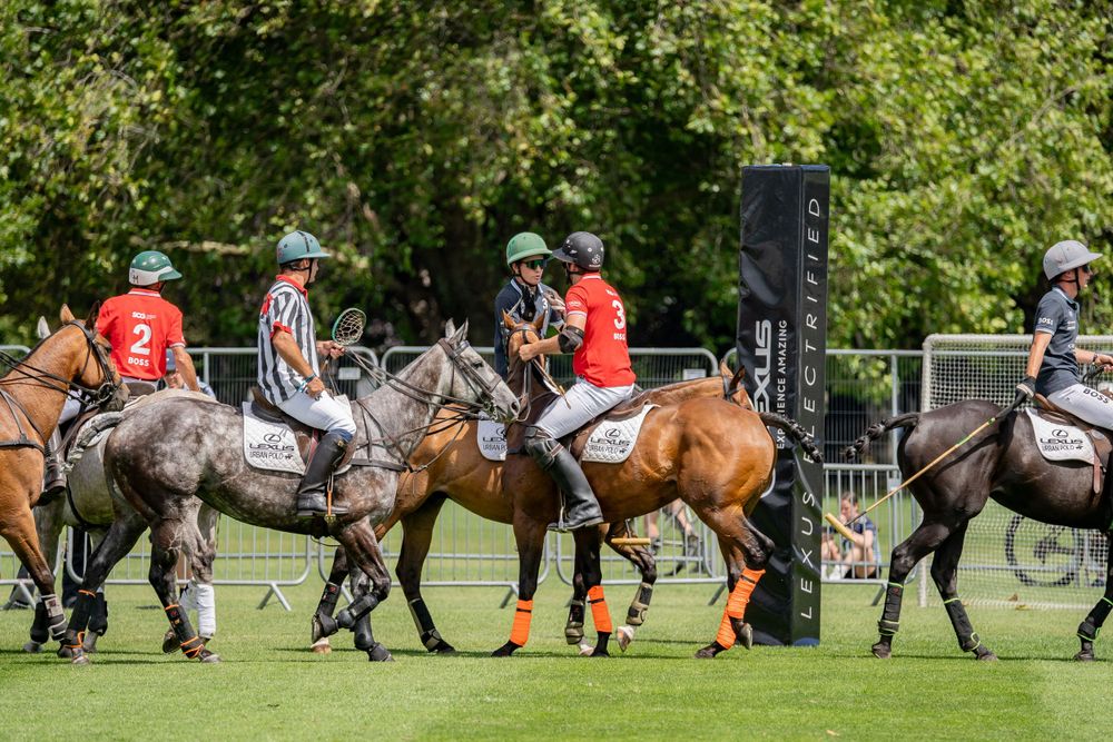 Multiple polo players on horseback engaged in active gameplay on green field.