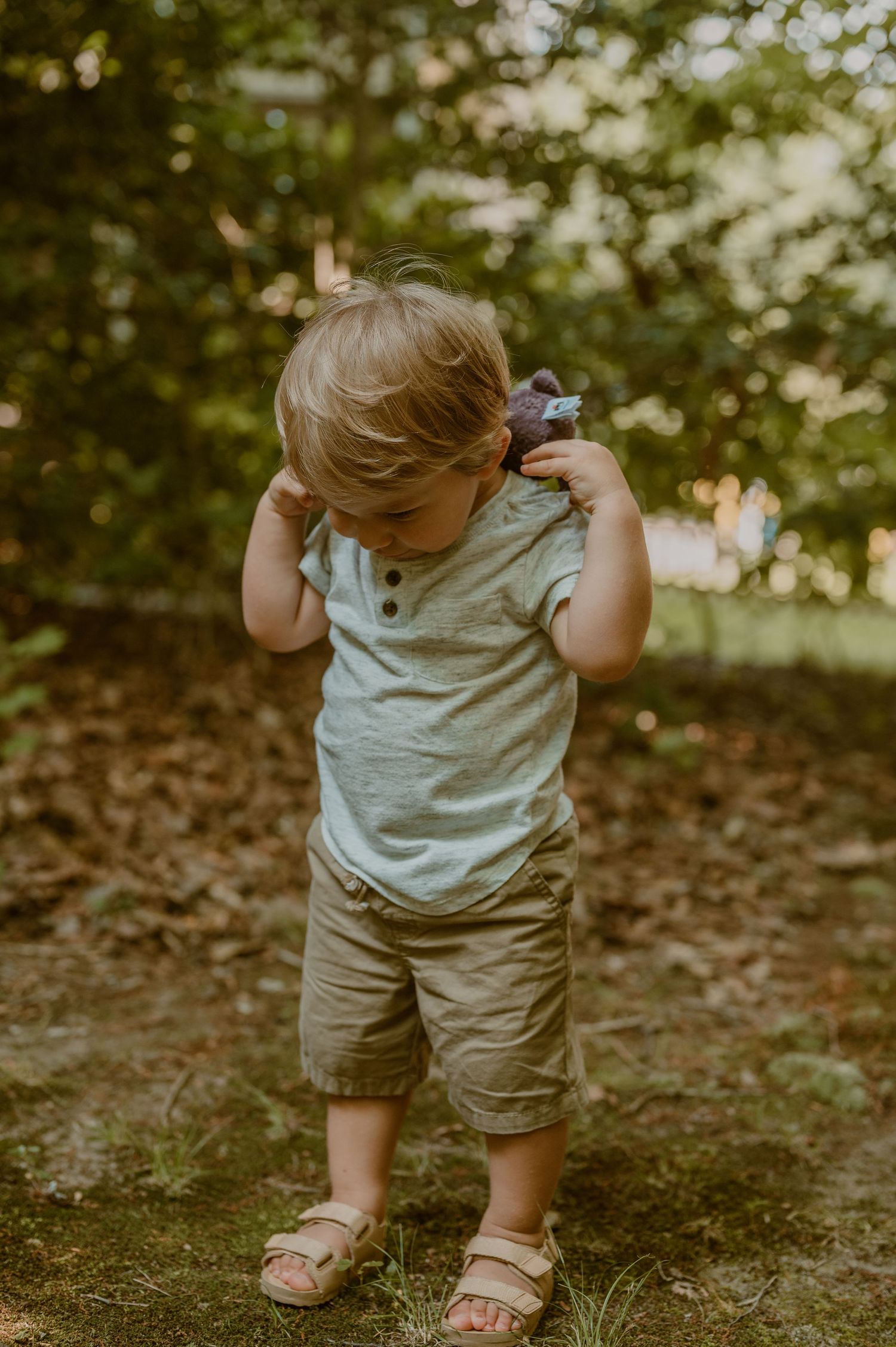 Samantha campbell imagery takes photo of toddler holding a favorite stuffed animal while outdoors in a garden setting.
