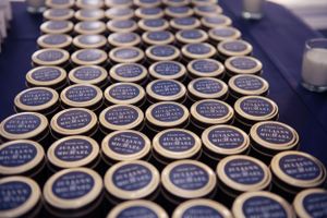 Rows of identical small blue-labeled jars arranged systematically on a dark surface.