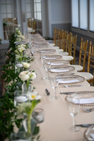 Elegant wedding reception table setting with beaded chargers and floral garland centerpiece.