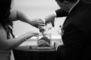 Black and white image of people pouring sand during a unity ceremony.