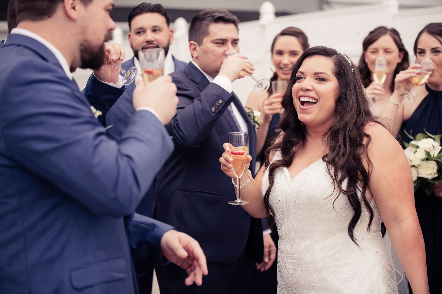 Wedding guests laugh and celebrate with champagne at an indoor reception.