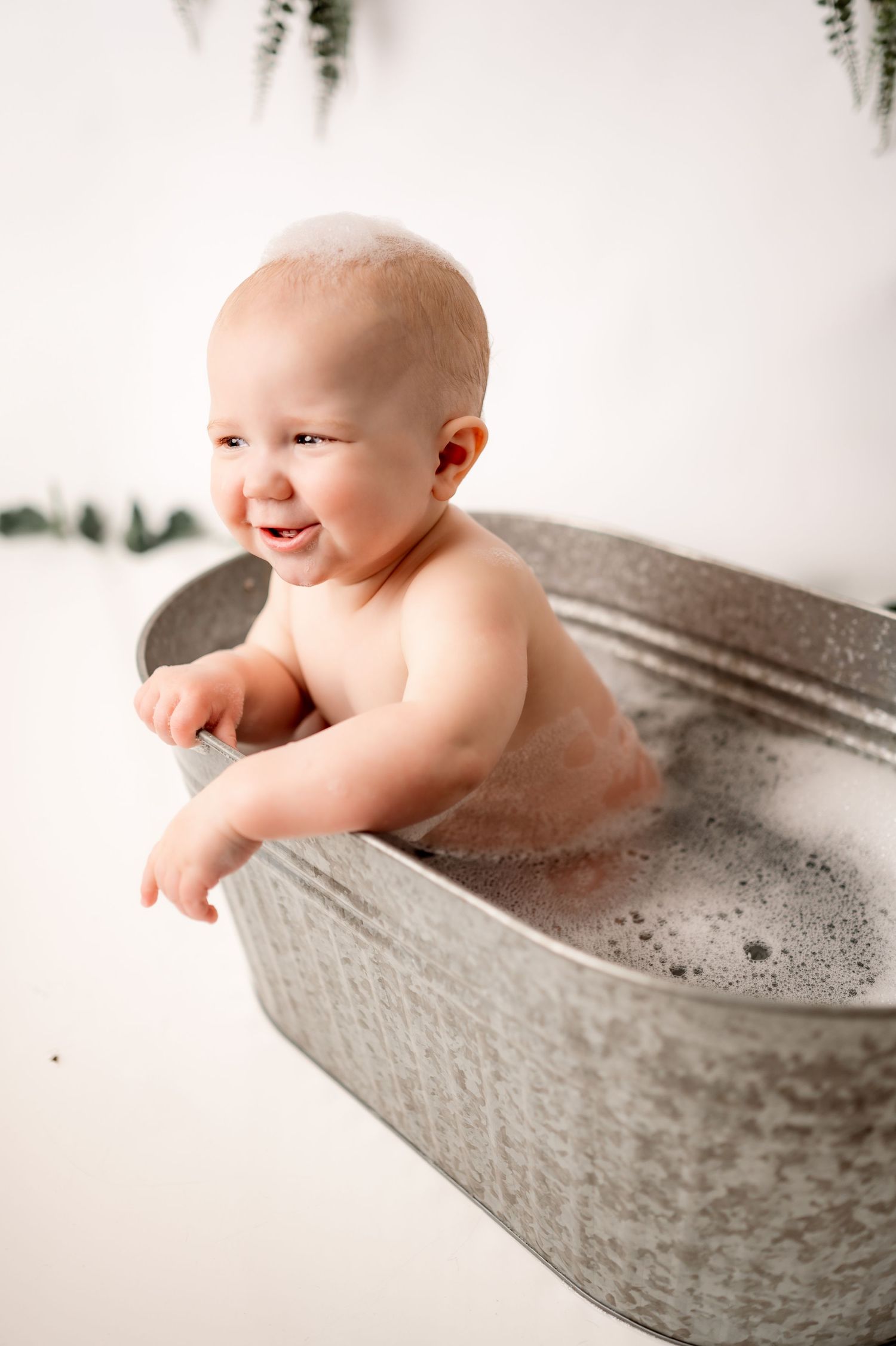 Playful bath time moment in grey metal tub with bubbles.