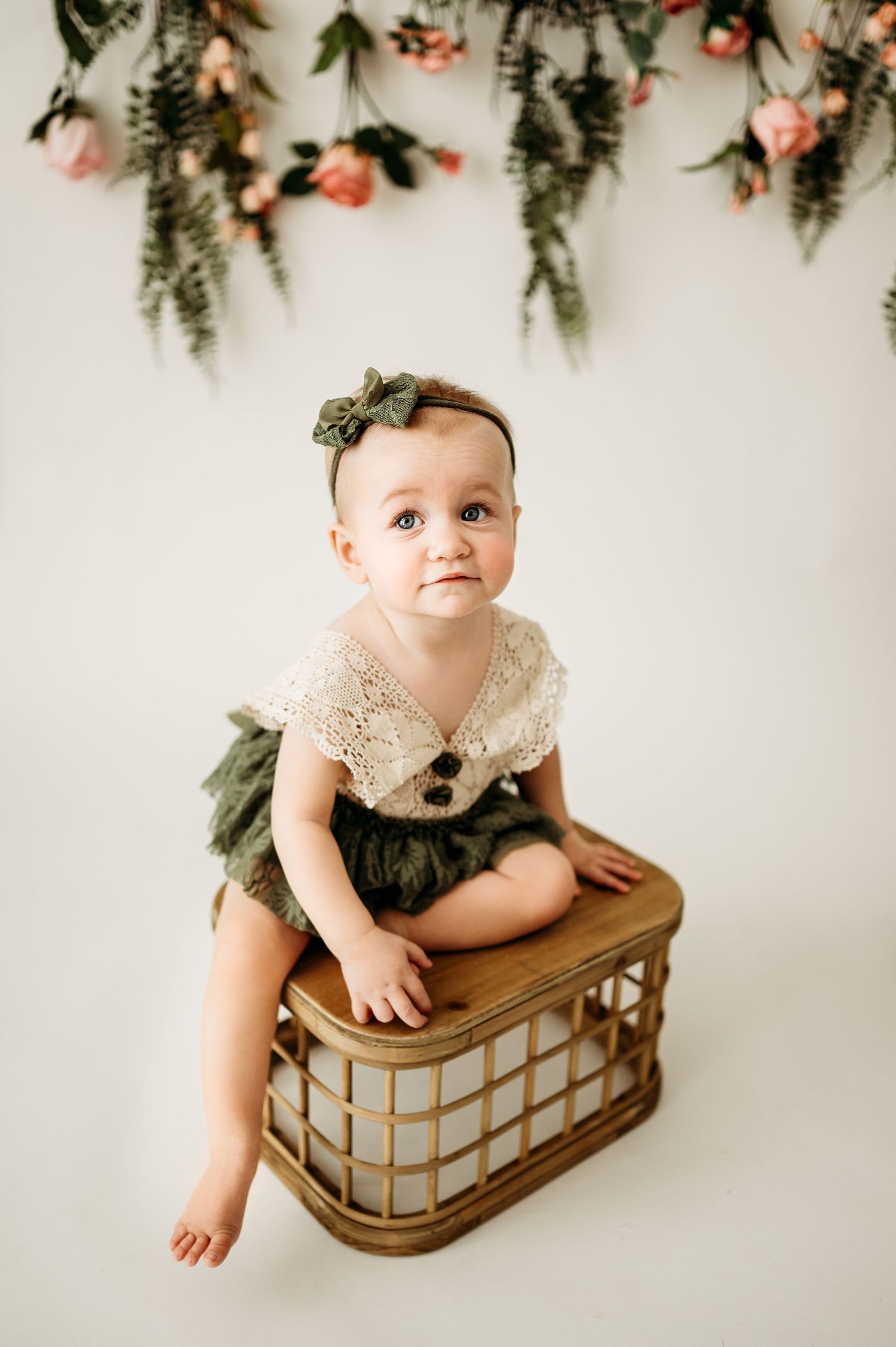 Vintage-style photo setup with bamboo basket and hanging floral decorations.