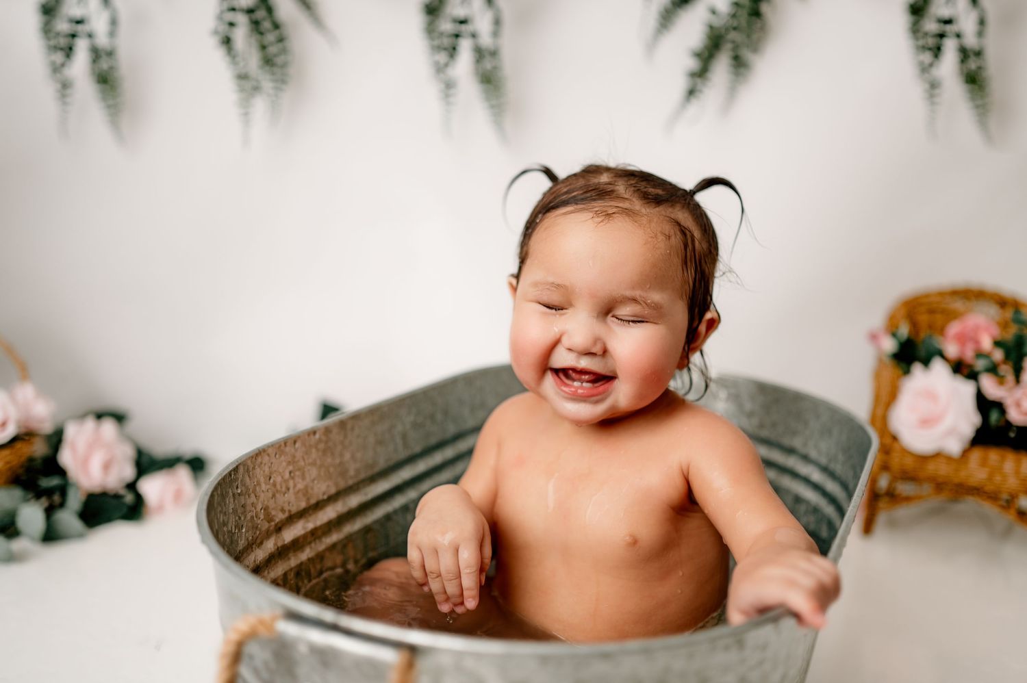 Joyful bath photography session in vintage galvanized tub with floral backdrop.