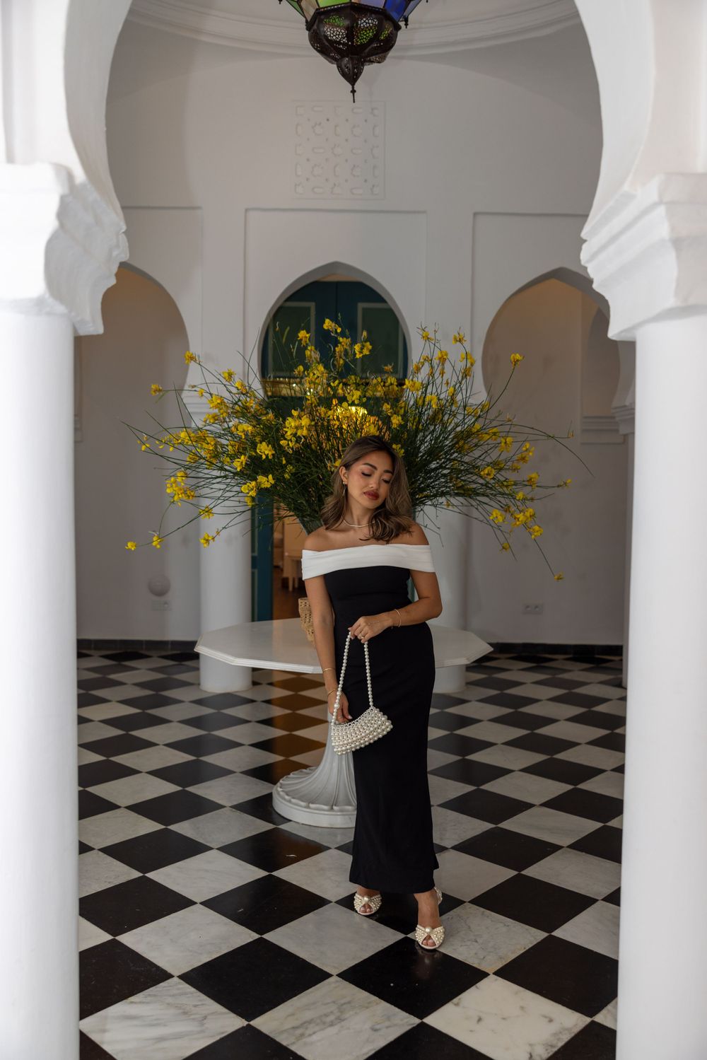 Elegant black and white checkered foyer with white arches and pillars featuring a dramatic yellow floral arrangement.