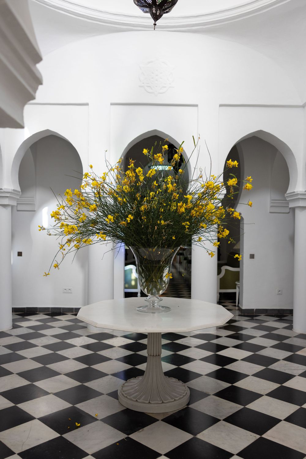Elegant foyer with black and white checkered floor featuring yellow flower arrangement on pedestal.
