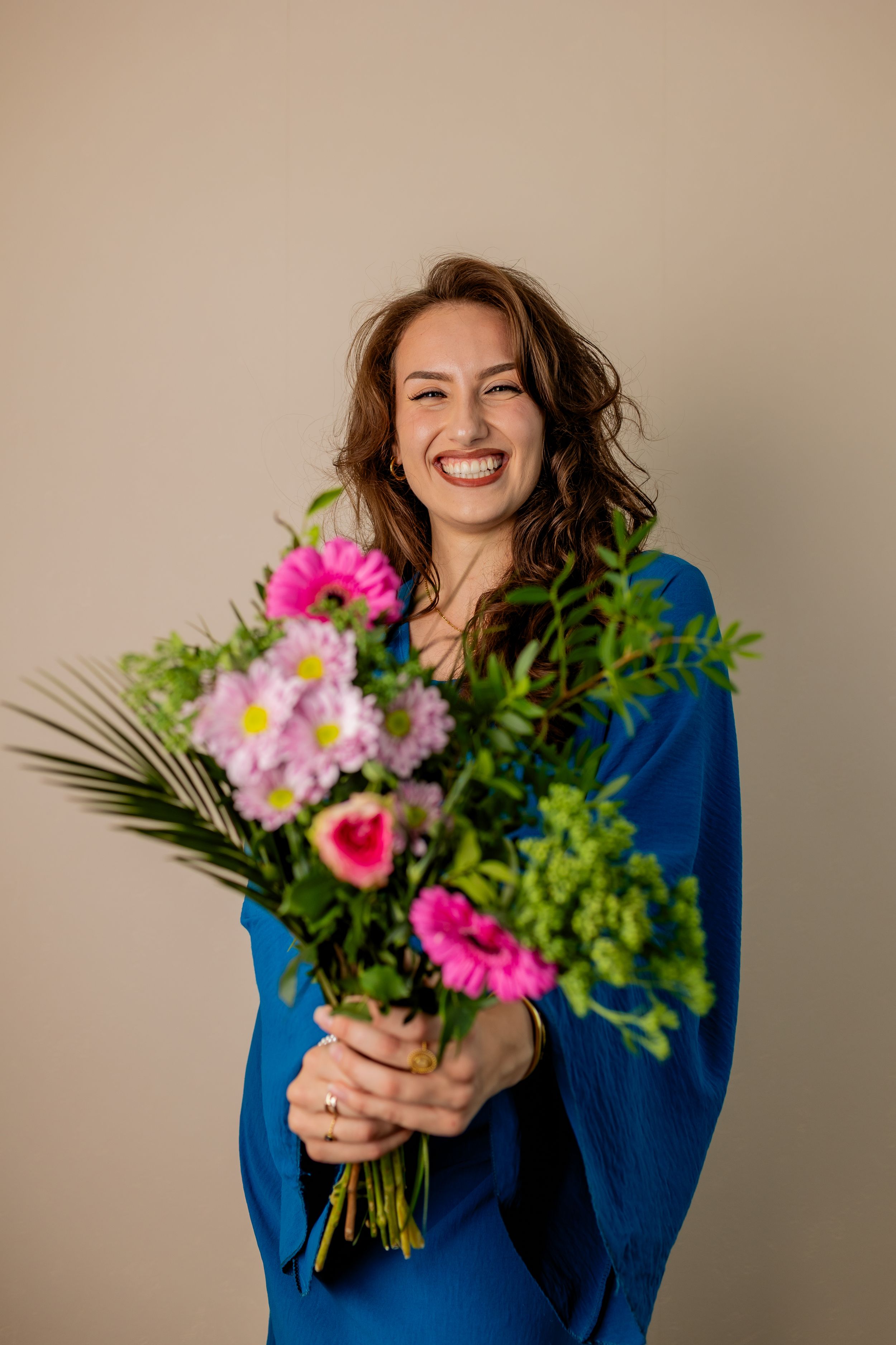 Portrait en intérieur studio avec un bouquet de fleurs, la femme est souriante et décontractée
