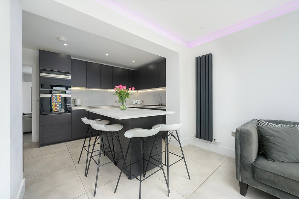 Modern open concept kitchen and living area with grey color scheme and LED accent lighting.