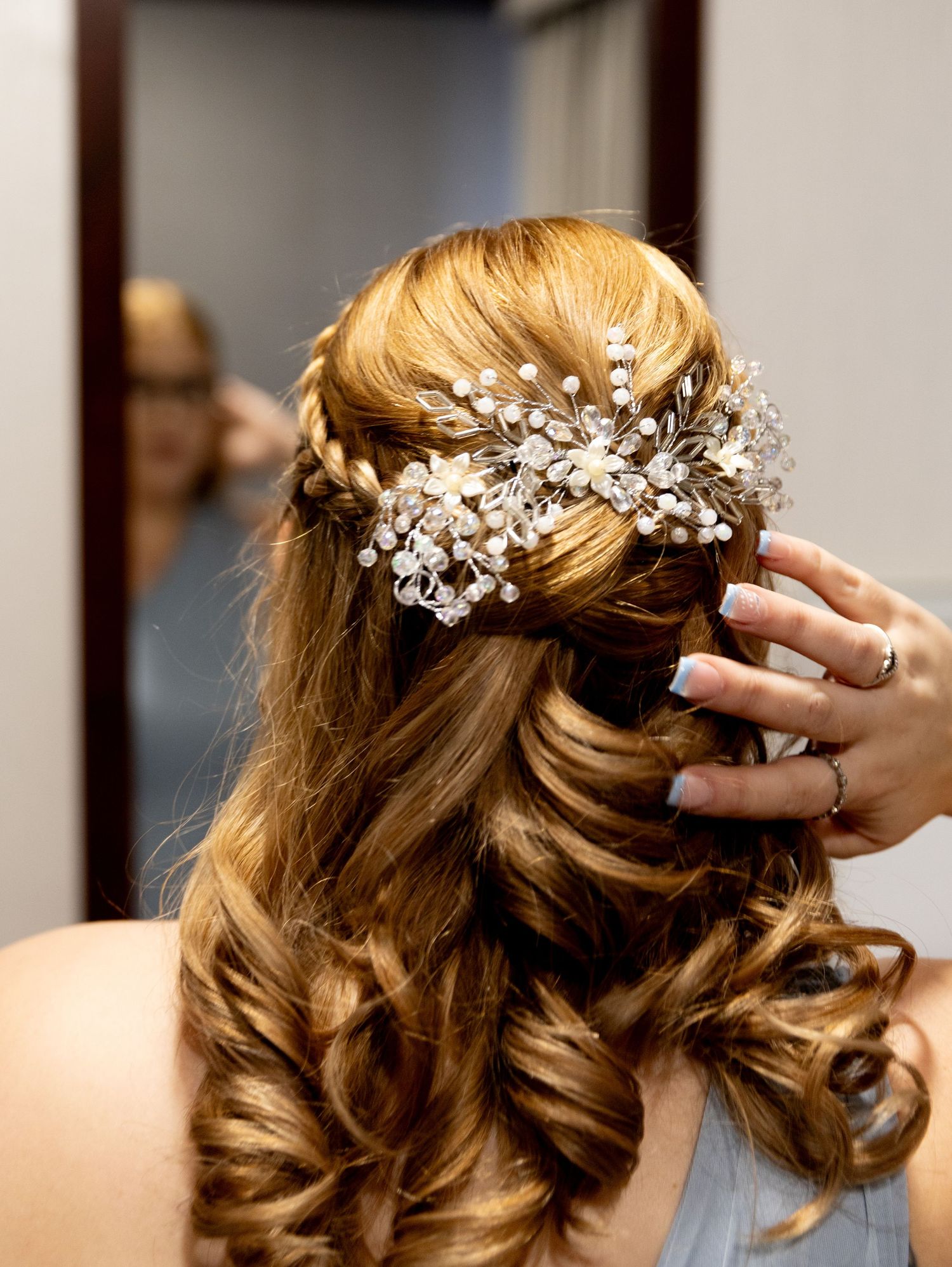 Elegant bridal hairstyle featuring crystal hair accessory with curled blonde waves.