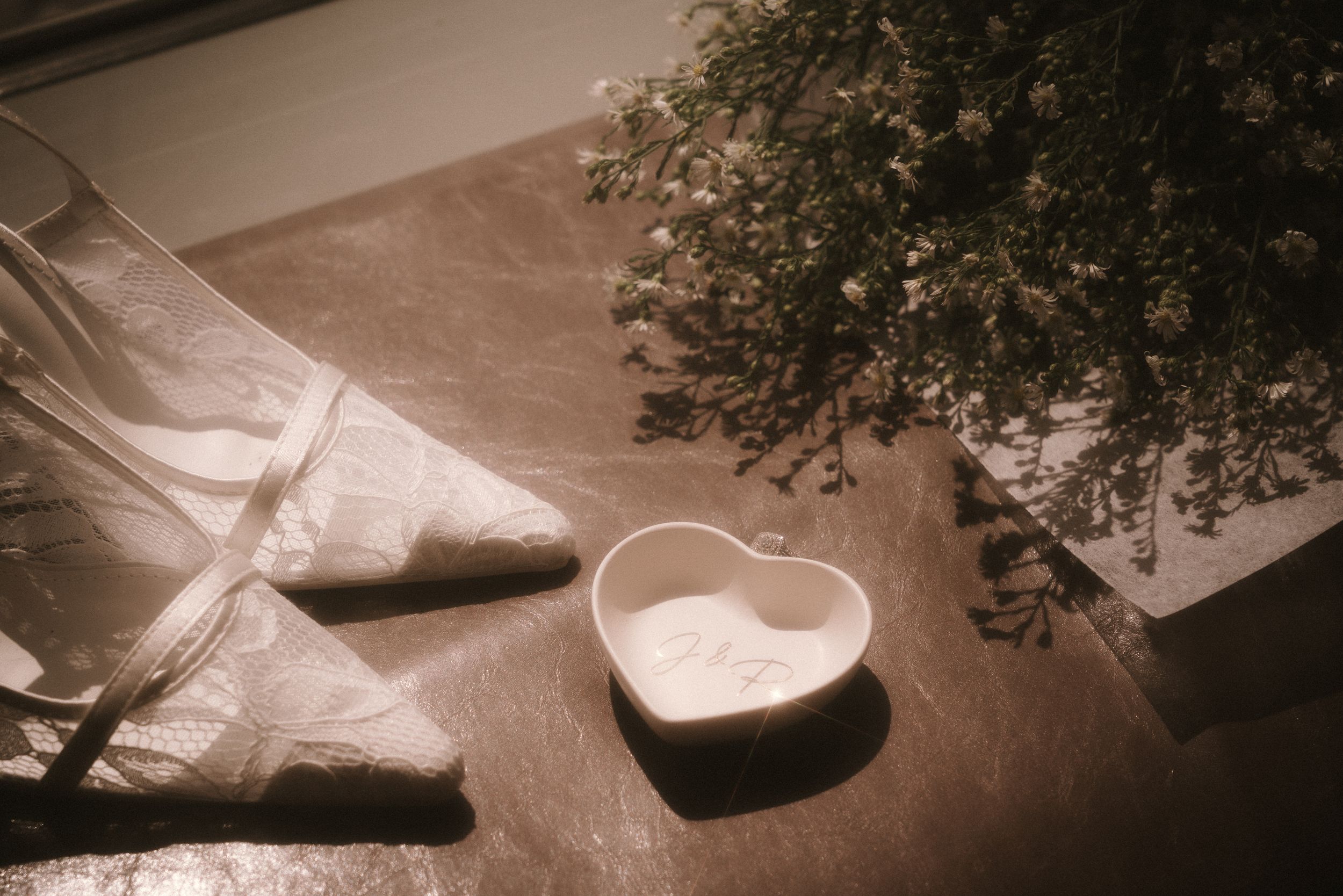 Wedding shoes and heart-shaped trinket dish in sepia tones.