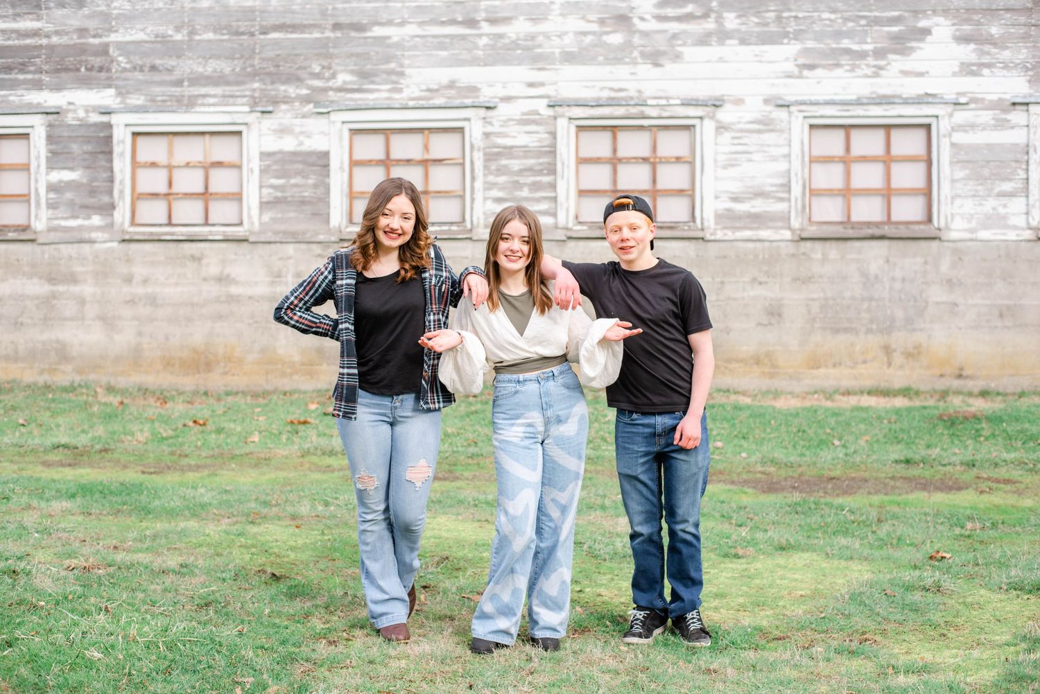 Casual group photo against weathered gray building exterior with window details.